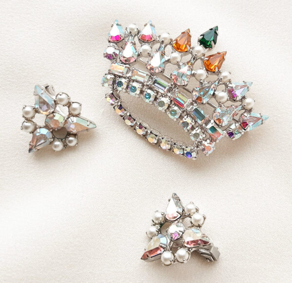 A set of brooches and earrings in the form of a crown with iridescent rhinestones and pearls.