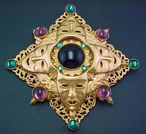 Brooch with masks with green and purple cabochons.