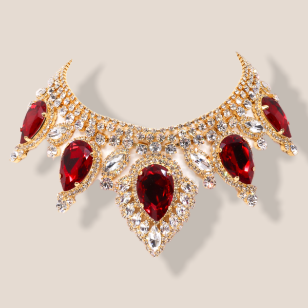 This gold tone necklace features a regal design with three dimensional hanging elements.