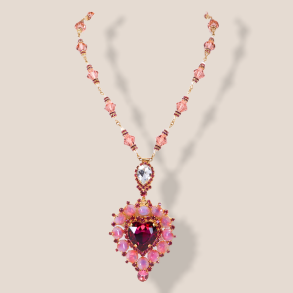 This gold tone necklace features an extra long necklace design with a three dimensional heart shaped central element.